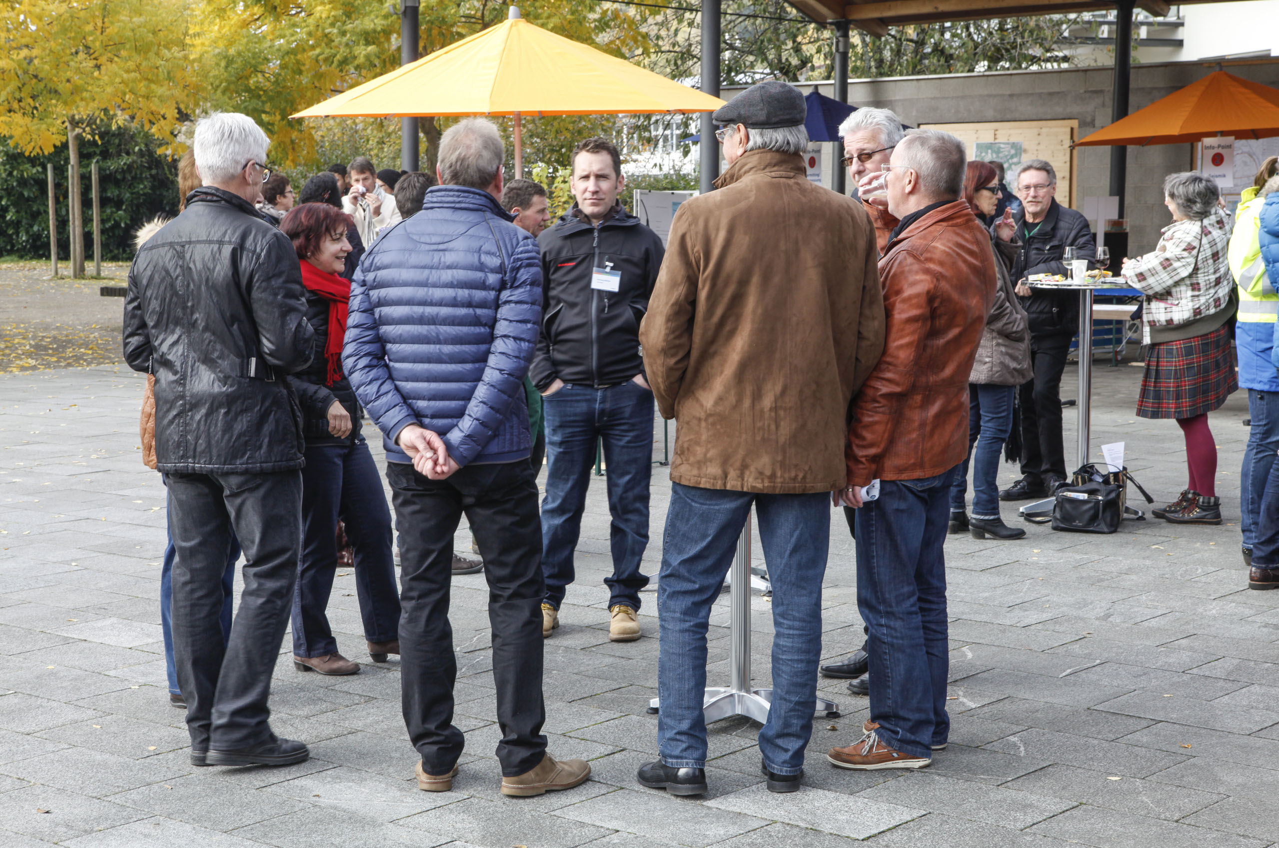 Einige Männer stehen auf einem öffentlichen Platz im Kreis und unterhalten sich